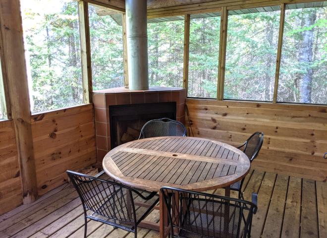 Screened porch area with seating and wood burning fireplace.
