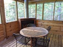 Screened porch area with seating and wood burning fireplace.