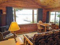 Living area with a futon, chair, gas fireplace, kitchen table, and a picture window capturing Lake Vermilion.